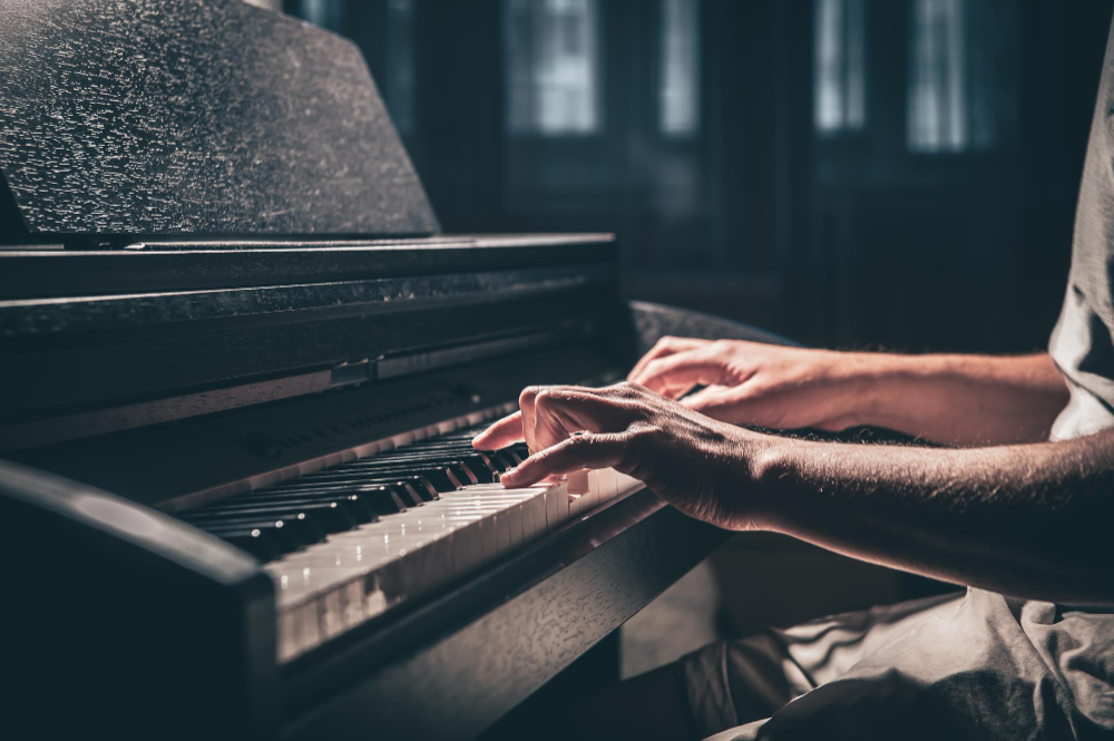 um homem toca um piano eletronico em um quarto escuro