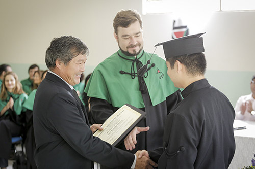 Eric Koudhi Omori recebendo o diploma das mãos do pai, Gilberto Mitsuaki Omori, membro da Comissão Permanente de Formatura há 15 anos
